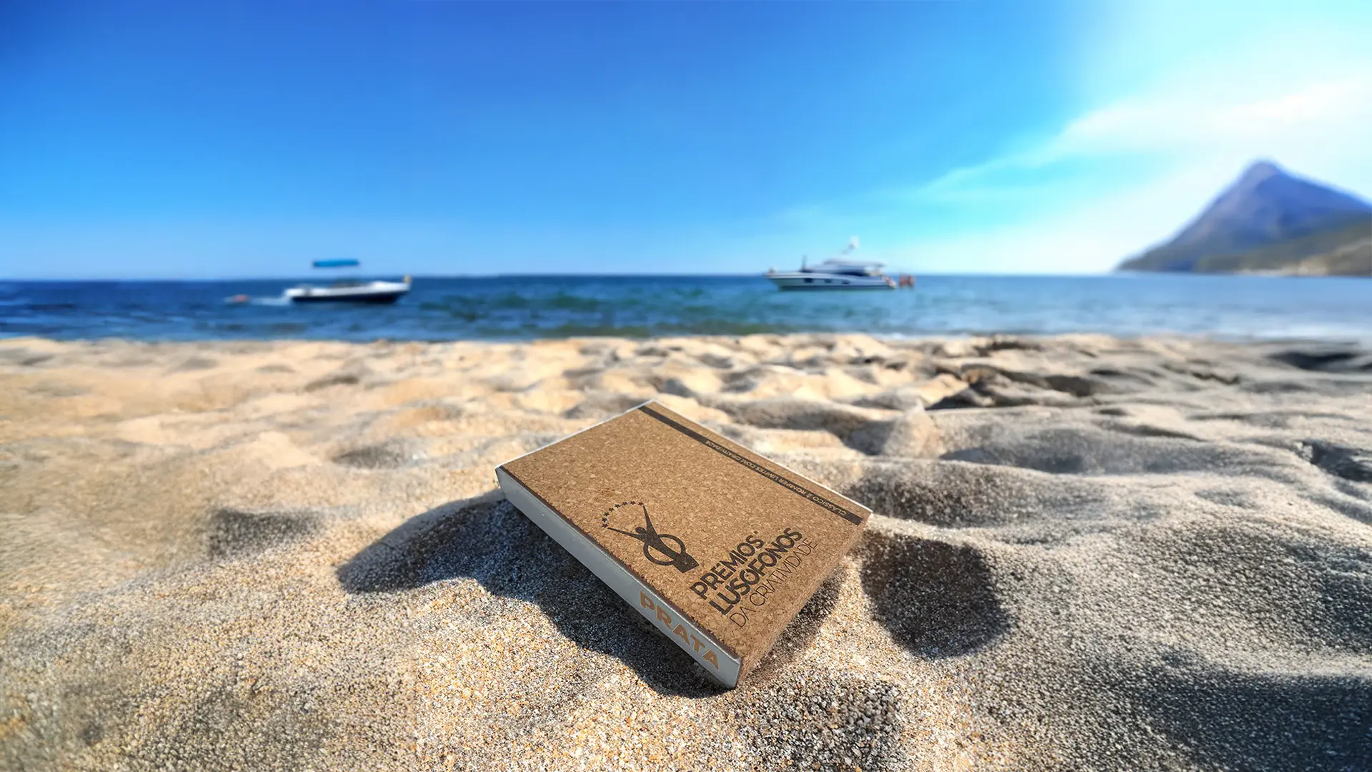 Troféu Prémios Lusófonos da Criatividade na areia da praia, simbolizando conquista internacional e criatividade premiada da Tekna Creative.